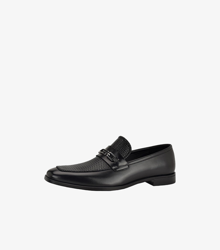 Three-quarter view of Guess men’s black slip-on loafer with smooth panels and polished metal hardware