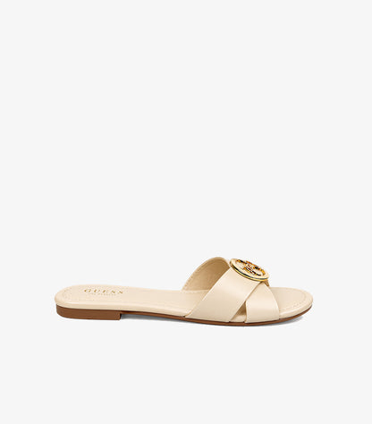 Side view of Guess cream slip-on sandal with crossover upper, circular logo hardware and slim flat sole