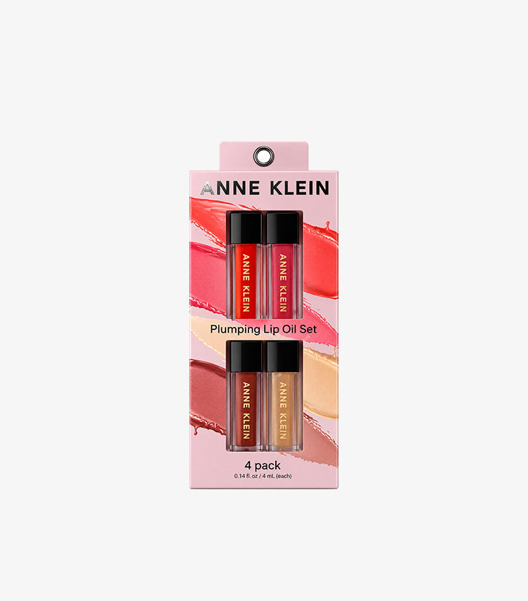 Anne Klein Plumping Lip Oil Set featuring four tinted lip oils in clear tubes with black caps and pink branded packaging, 4ml each.