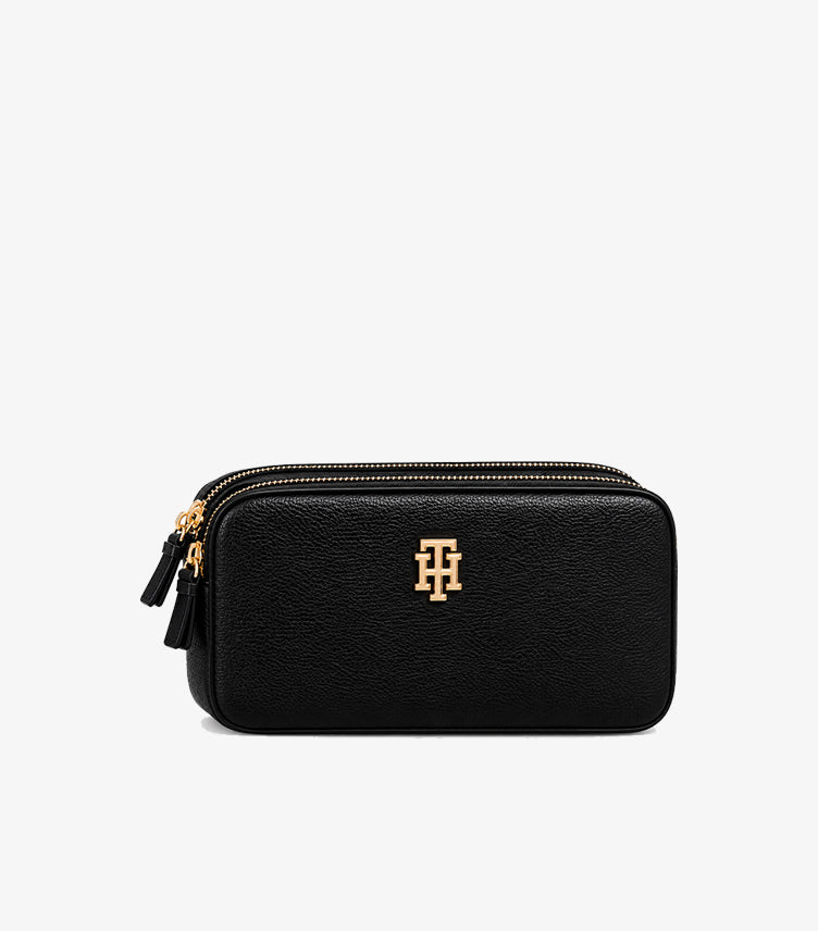 Close-up of Tommy Hilfiger textured camera bag featuring dual zip closures and gold-tone logo hardware
