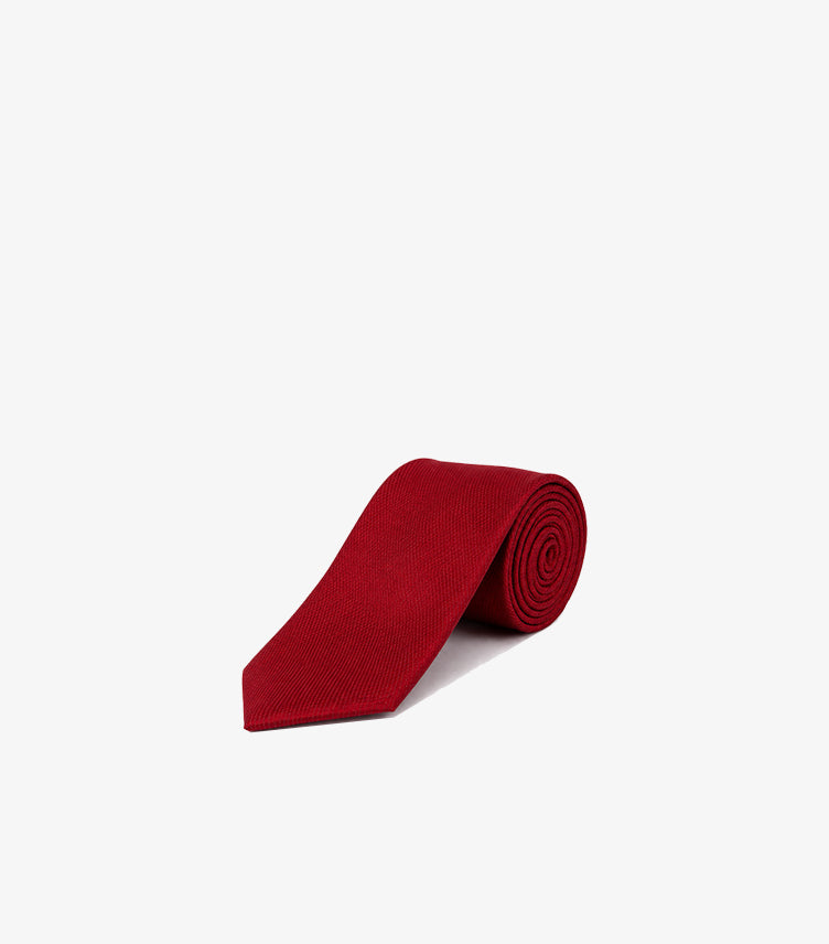 Tommy Hilfiger men’s solid red textured necktie rolled with pointed blade displayed on a white background